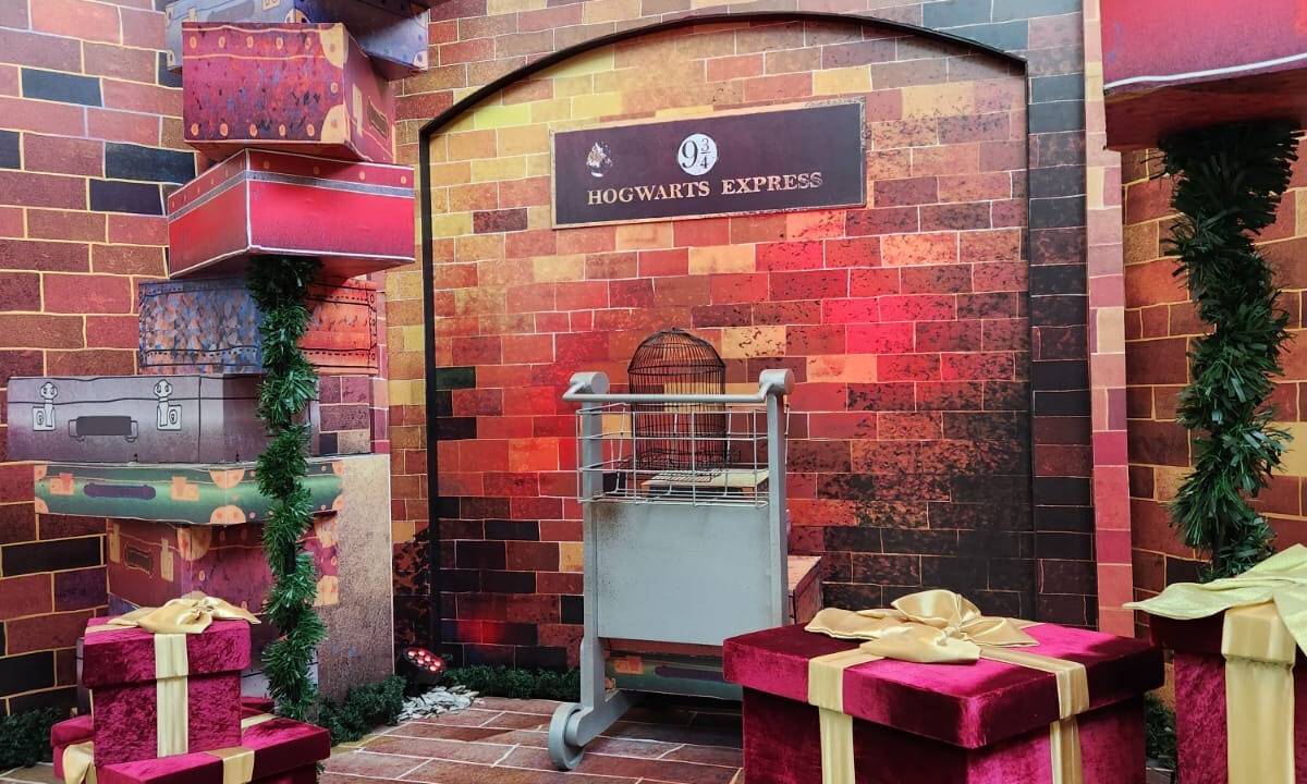 Uma parede falsa de tijolos vermelhos que imita com uma plaquinha escrito "Hogwarts Express", do filme Harry Potter.
