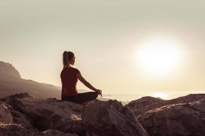 Young woman practices yoga and meditates on the mountain