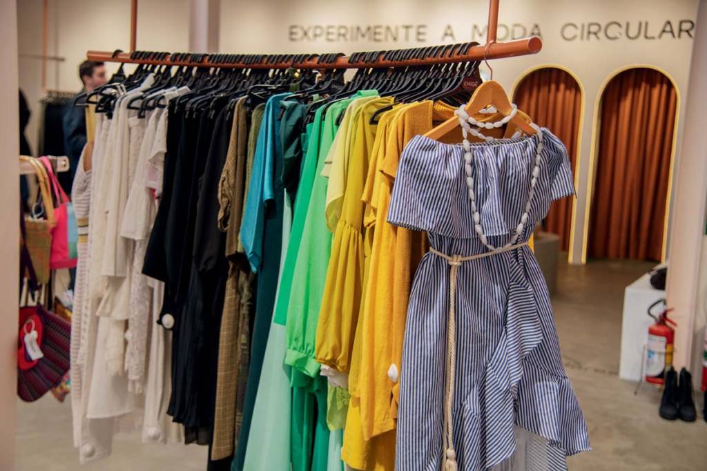 Foto exibe arara com roupas divididas por cor.
