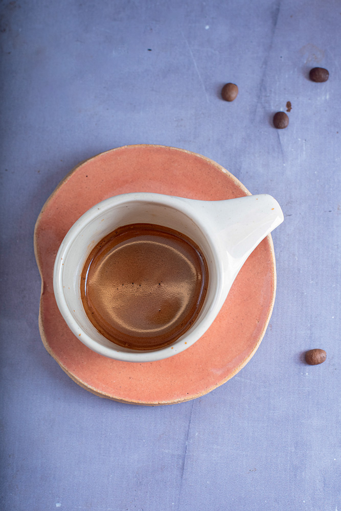 Foto tirada de cima de uma xícara branca com café de cor chocolate.