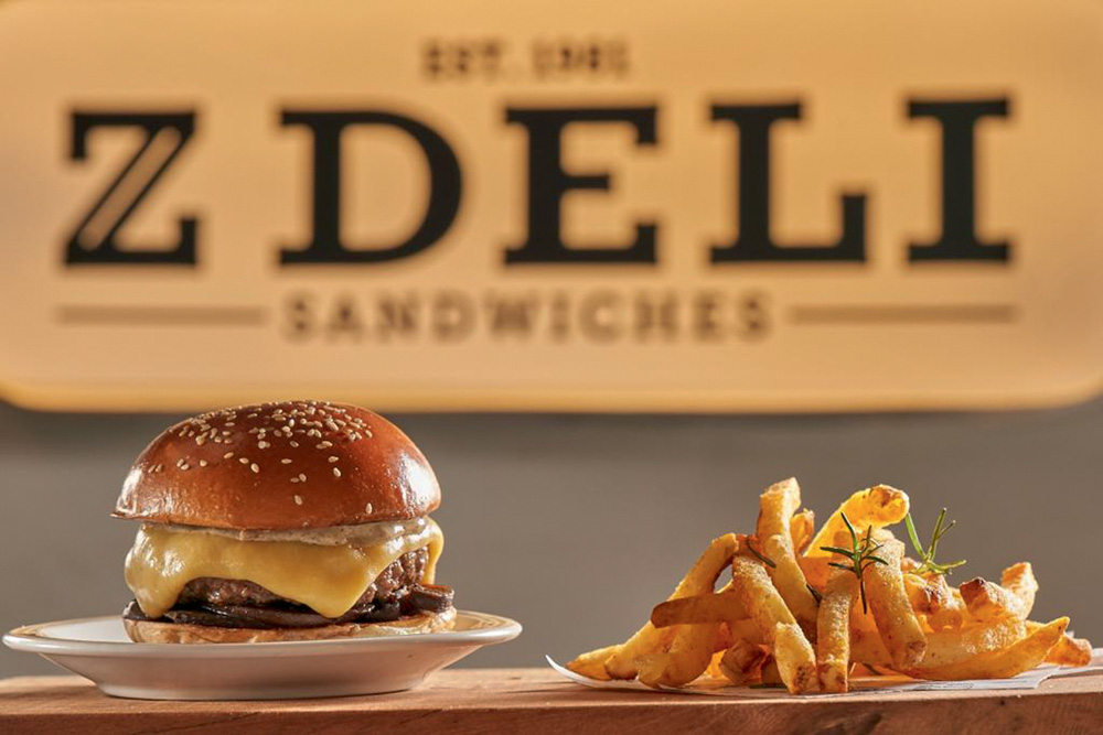 Circuito Comer & Beber – Z Deli Sandwiches Perfil de hambúrguer com queijo derretido ao lado de fritas