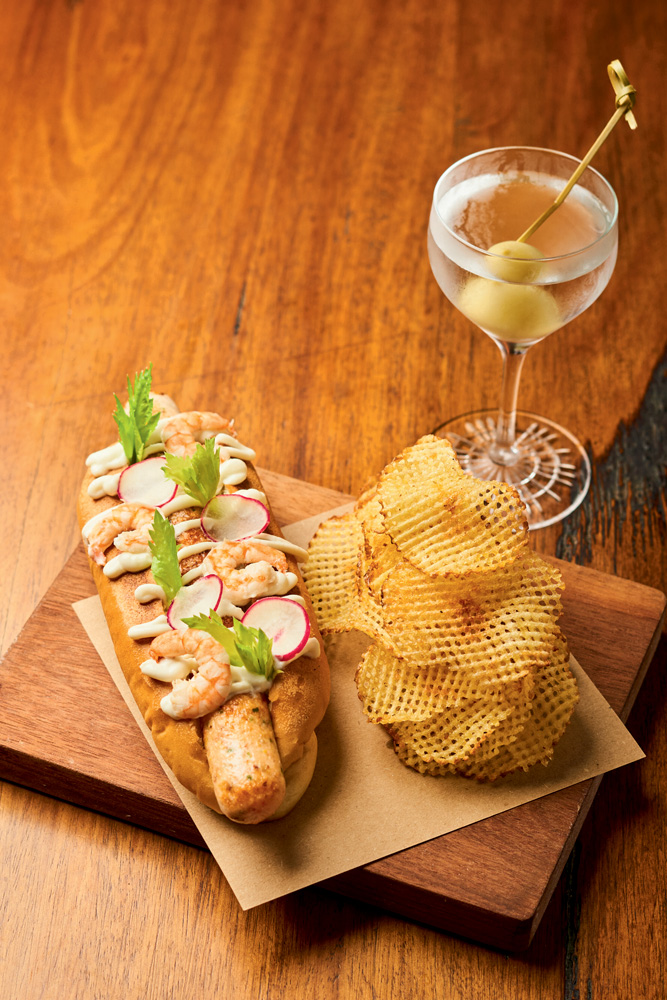Circuito Comer & Beber – Astor Cachorro-quente ao lado de batatas fritas rendadas em prato retangular de madeira ao lado de dry martini