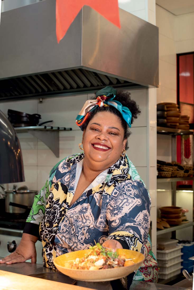 Altar Cozinha Ancestral mulher-com-roupas-coloridas-e-lenço-no-cabelo-sorrindo-e-entregando-prato-de-comida-em-cozinha