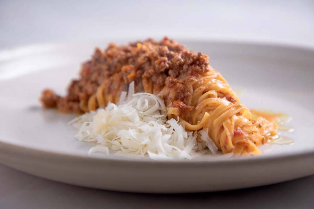 linguine-enrolado-em-prato-de-louça-branca-com-ragu-de-carne-e-queijo-ralado