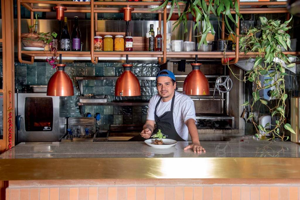 Feriae – Mario Panezo chef-de-cozinha-atrás-de-boqueta-de-avental-e-bone