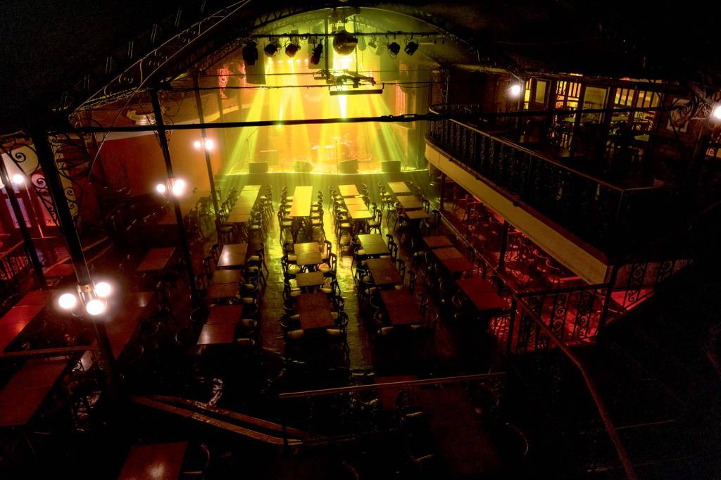 Foto vista de cima da pista do Bourbon Street, com luzes amarelas no palco e mesas.