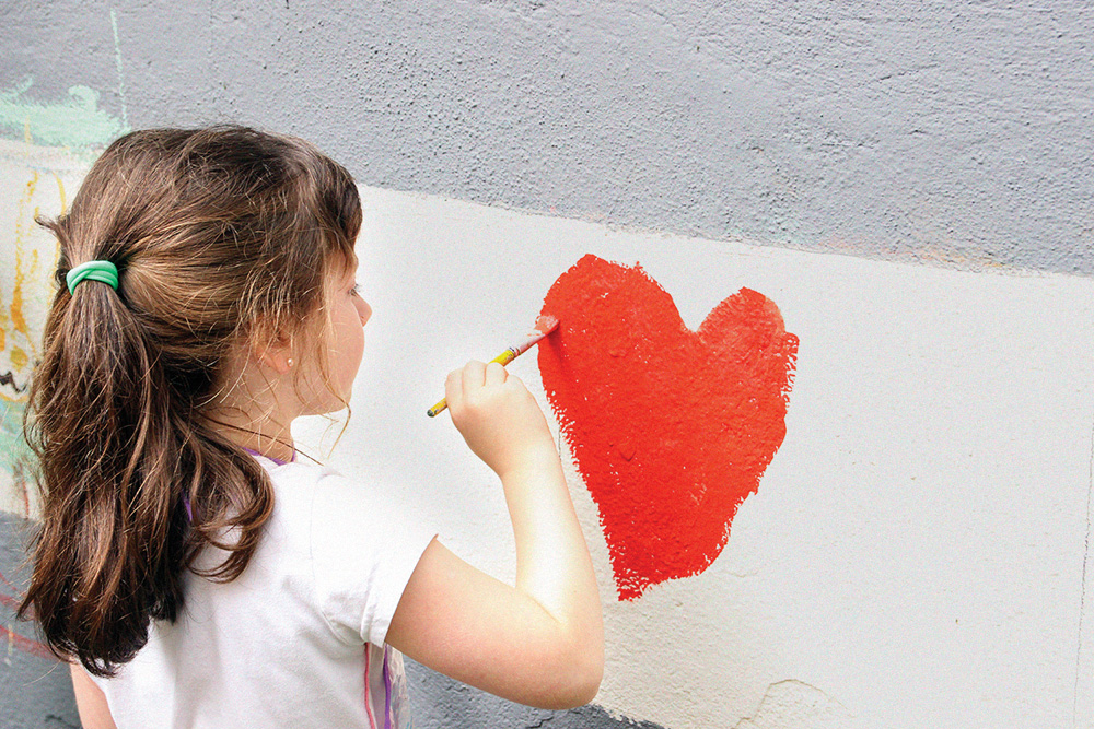 colégio humboldt Imagem mostra aluna pintando coração vermelho com tinta em parede