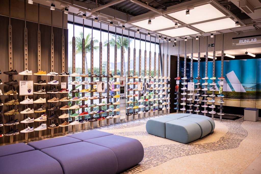 01_House of Sports_Adidas_RJ_Crédito RenanOlivetti Loja com sofás cinzas e prateleiras de tênis abaixo de janela de vidro