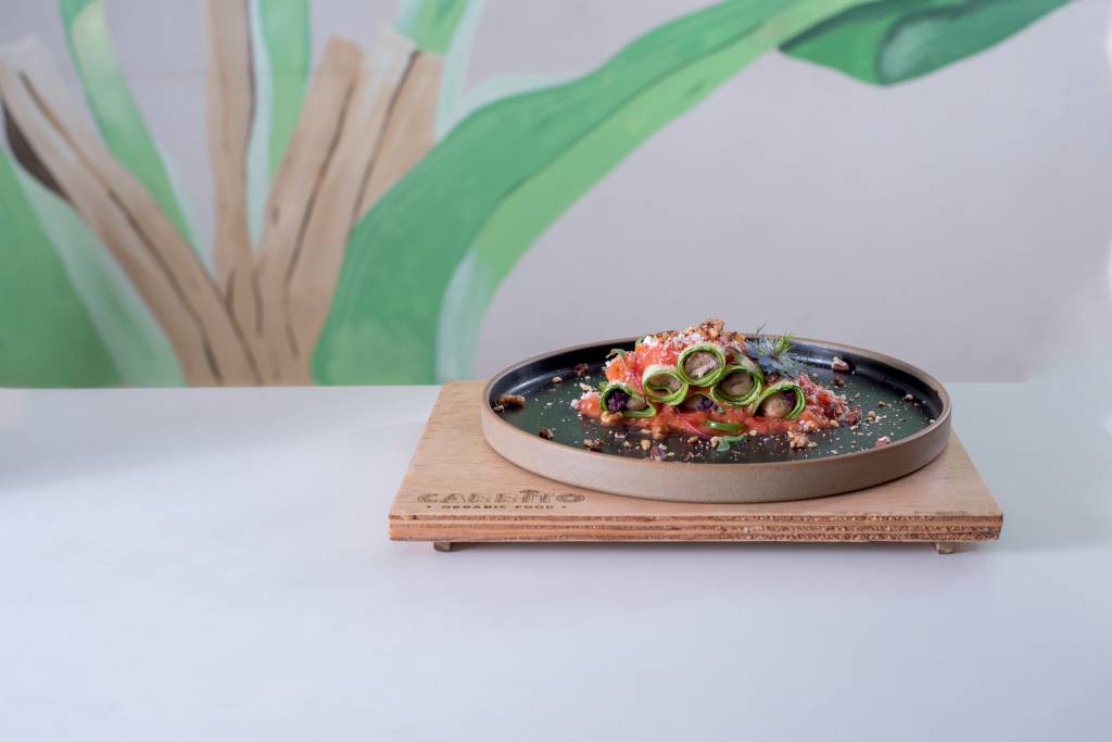 prato de cerâmica sobre suplat de madeira em cima de mesa com canelones de legumes.