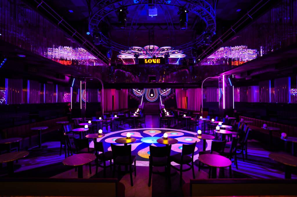 Love Cabaret Feita de cima, foto exibe pista de dança circular com muitas luzes rosadas, chão iluminado com desenhos circulares e estrutura de ferro no topo.
