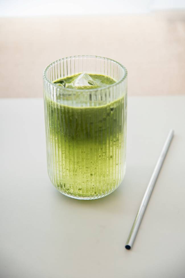 Copo com bebida matchá tônica de cor verde e canudo