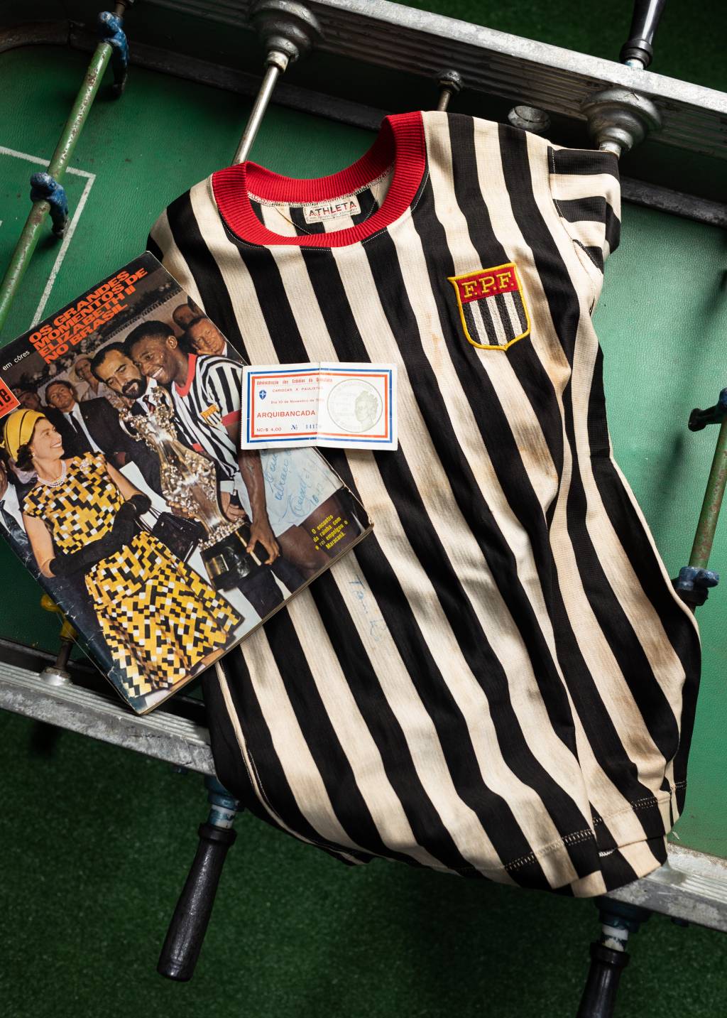 CASSIOCOLECCAMISAS32 Foto de camisa listrada em preto e branco com brasão e foto de Pelé à esquerda