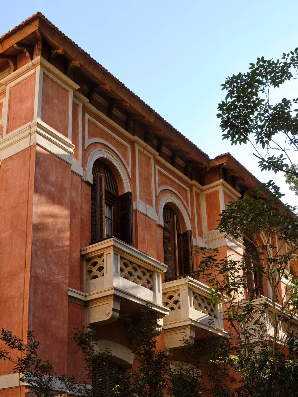 Foto em close de fachada de prédio laranja com terraço