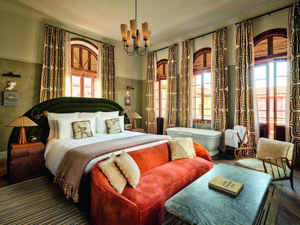 Soho House São Paulo-Crédito Soho House-Divulgação (2) Foto de quarto de casal com sofá laranja à frente e lustre