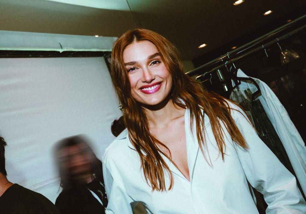 Mulher loira sorri e veste camisa branca