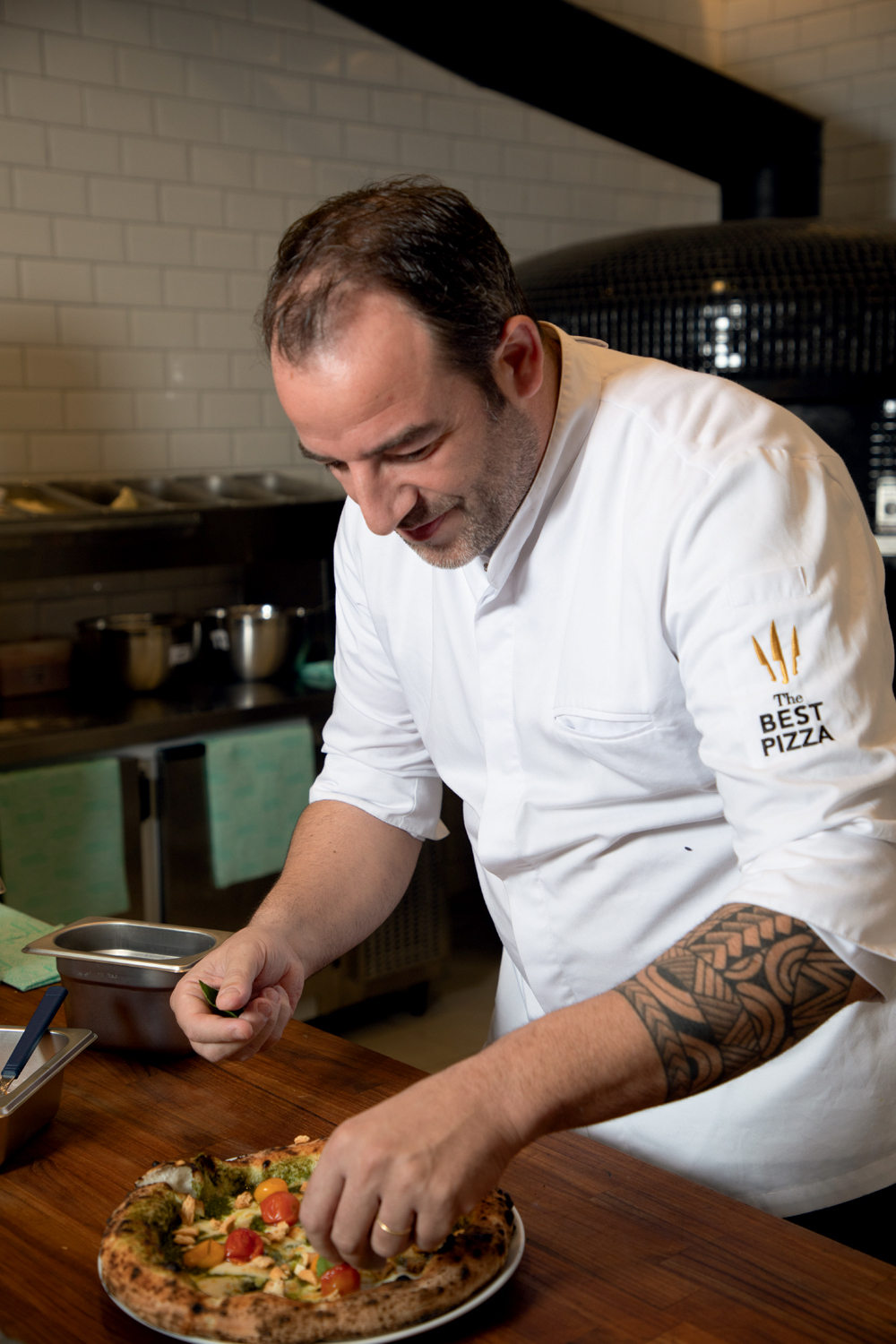 Soffio Pizzeria Chef de cozinha de dólmã finalizando pizza sobre balcão.