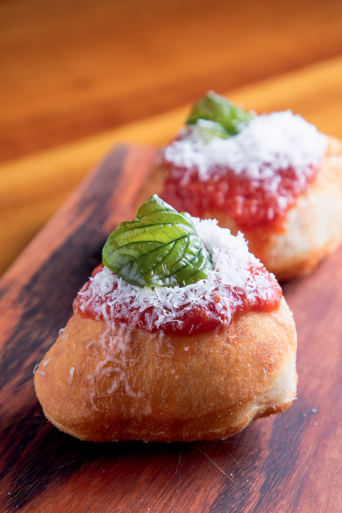 Soffio Pizzeria Dois bolinos de massa assada cobertos por molho de tomate, queijo ralado e folha de majericão.