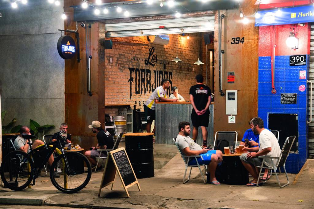 Fachada da cervejaria Los Forajidos com pessoas sentadas em mesinhas dobráveis na calçada.