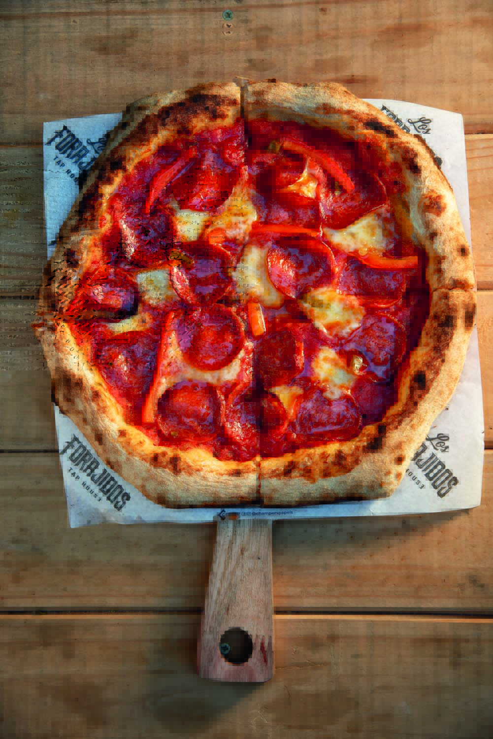 Foto aérea de pizza de pepperoni sobre mesa de madeira.