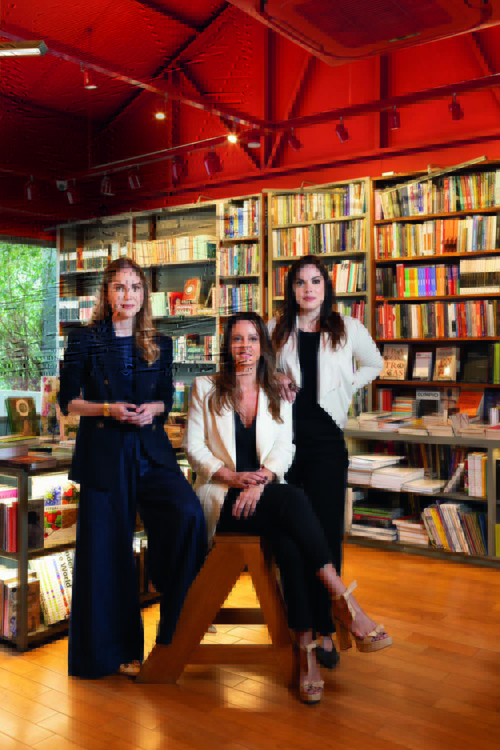 Trio do livro Precisamos Falar de Consentimento Crédito Simone Marinho-Divulgação (2).jpeg Três mulheres posam em livraria, uma sentada e duas de pé