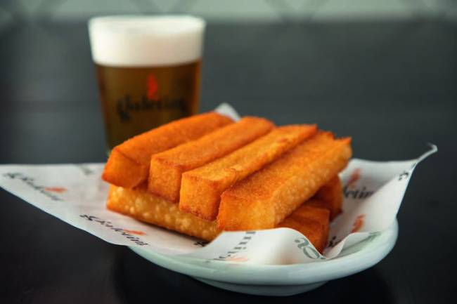 Porção de polenta frita com cerveja atrás