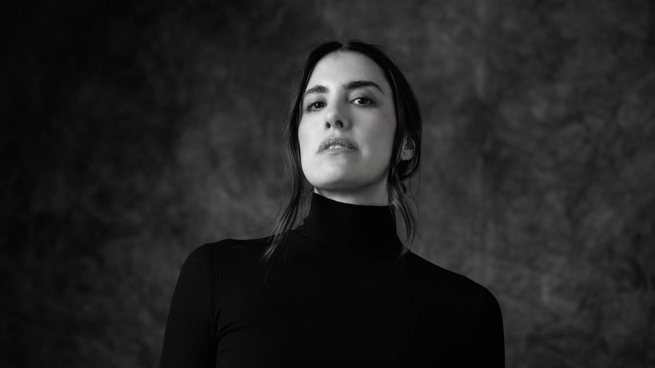 Foto em preto e branco, retrato de mulher com cabelo preso e suéter preto