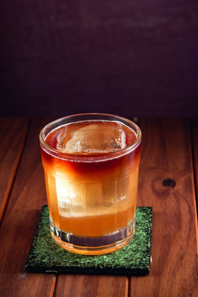 Alcova Drinque no copo com gelo em cima de mesa de madeira