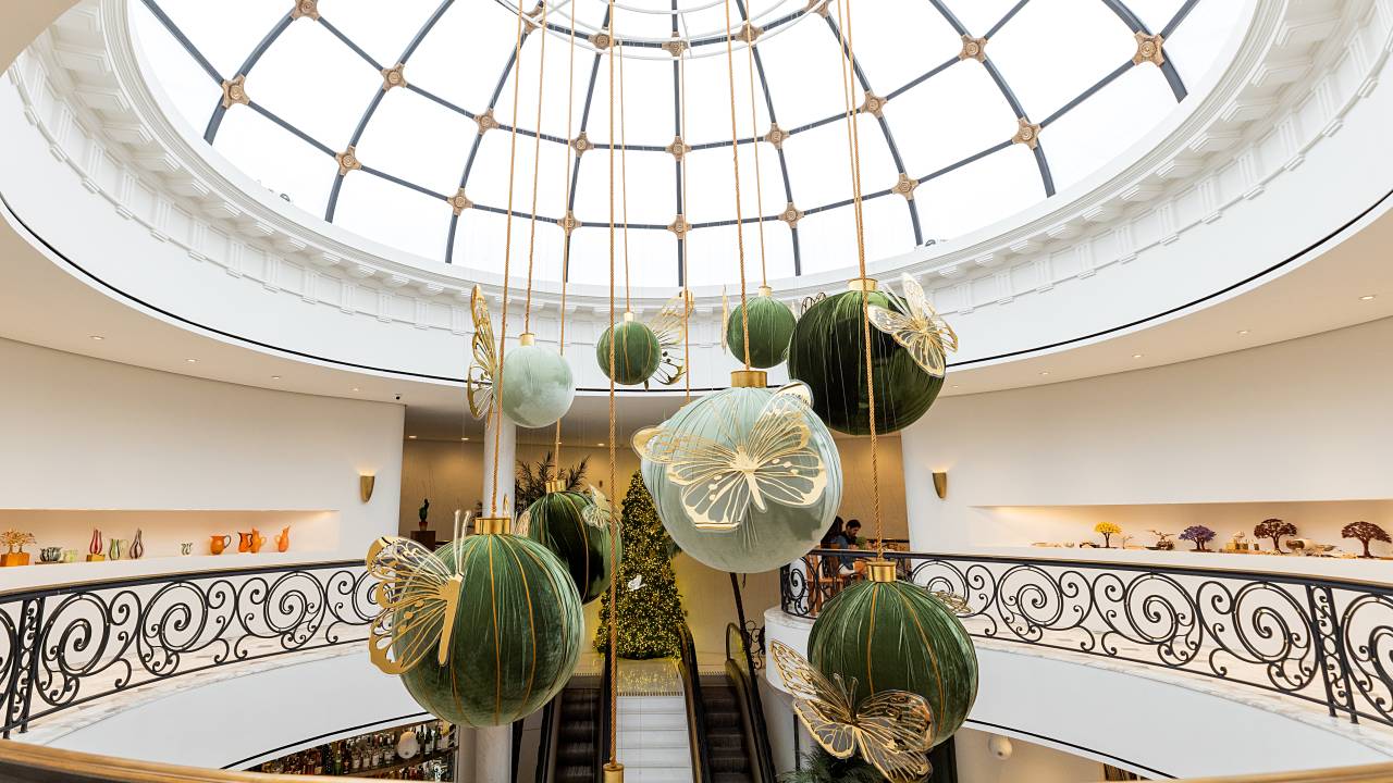 Decoração natalina na Tania Bulhões com árvore ao fundo após escadas rolantes. À frente, bolas verdes e brancas gigantes