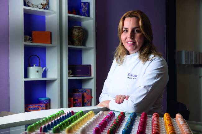 Mulher sorrindo com bombons de chocolate coloridos na frente