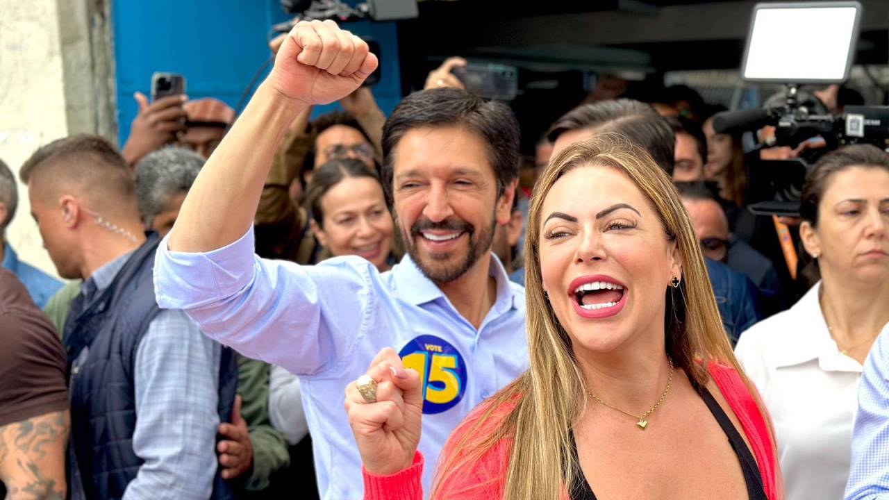 Duas pessoas sorrindo e levantando o braço