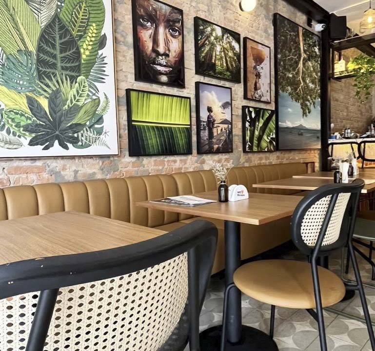 Salão do bar com mesas e cadeiras e quadros na parede