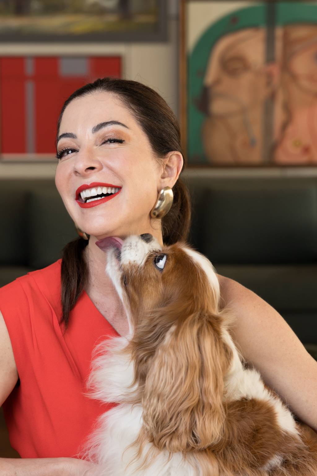 Ana Paula Padrão Crédito Wanezza Soares-VejaSP (03) Mulher branca de peça alaranjada posa sorrindo com cachorrinho lambendo seu queixo