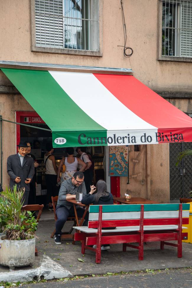 Toldo na fachada de uma pequena loja com bancos na frente