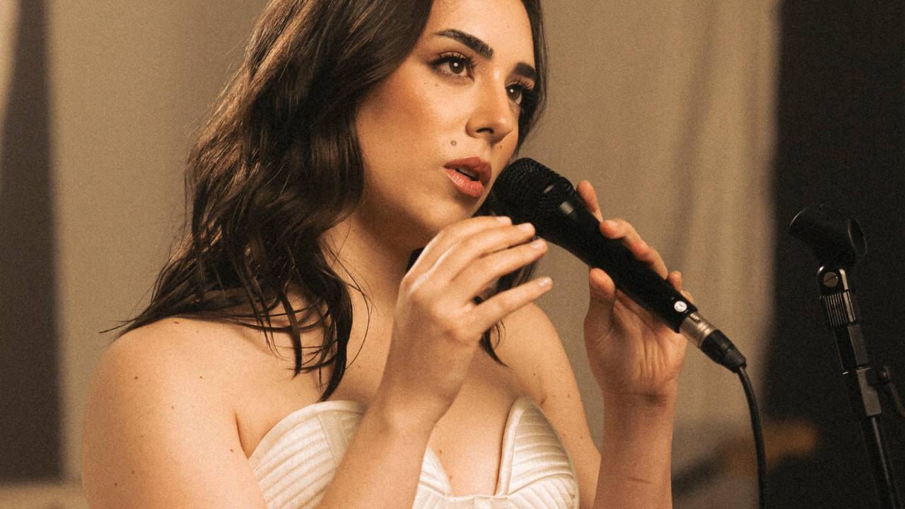 A cantora e compositora Lara Silva segurando microfone e vestindo peça branca