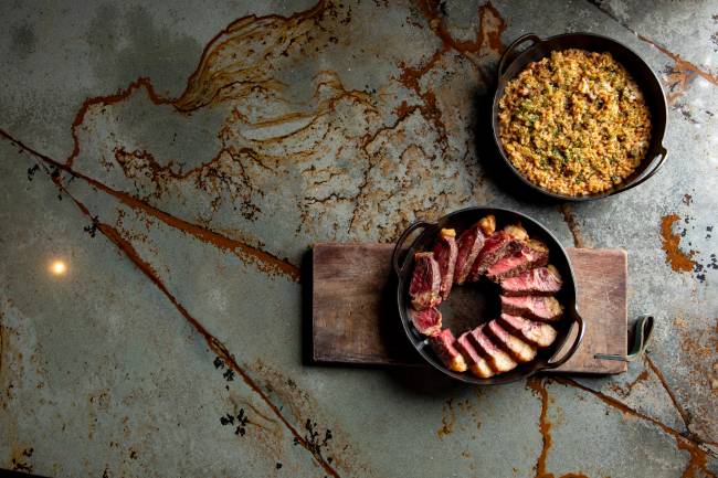 duas panelas de ferro preta, uma com dry aged com arroz de tutano