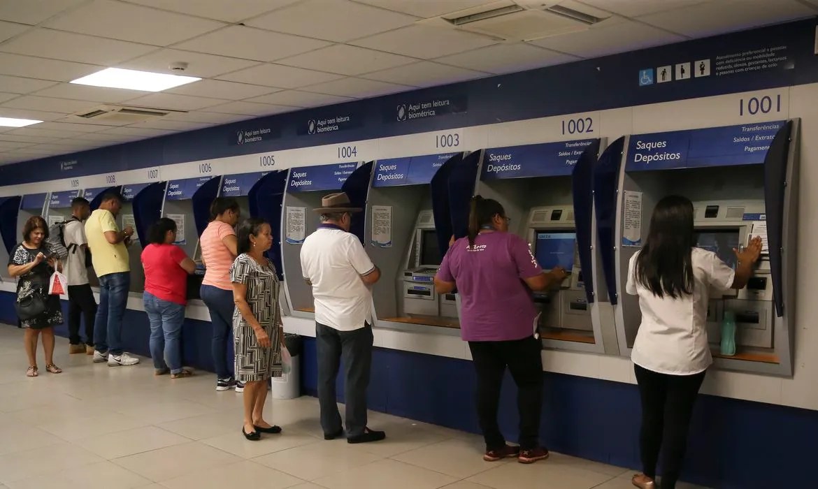 Pessoas no caixa eletrônico de um banco