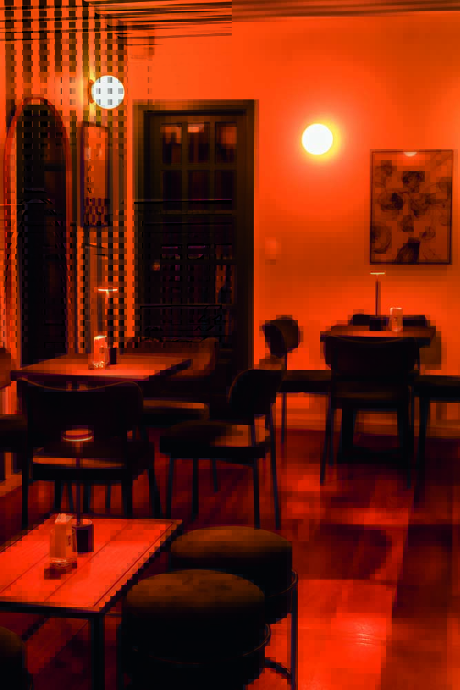 ambiente_The Door_Feltran Foto-9.jpeg Salão com mesas e cadeiras e luz baixa