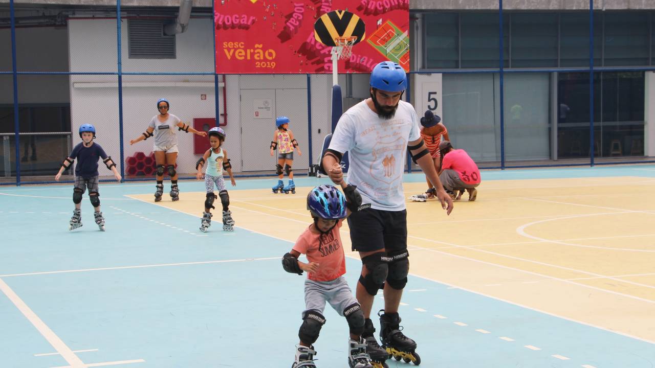 Criança e pai andam de patins em quadra
