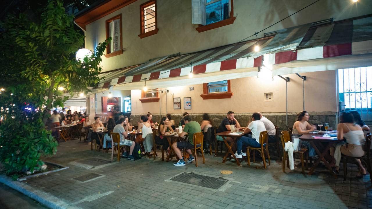 Muitas pessoas na calçada em mesas de madeira
