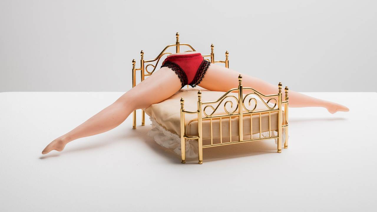 Pernas abertas com calcinha vermelha em cima de uma cama dourada, obra artística