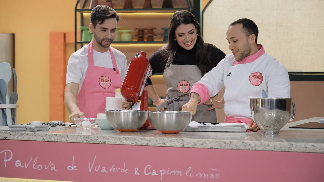 Três pessoas fazendo um doce em uma bancada rosa