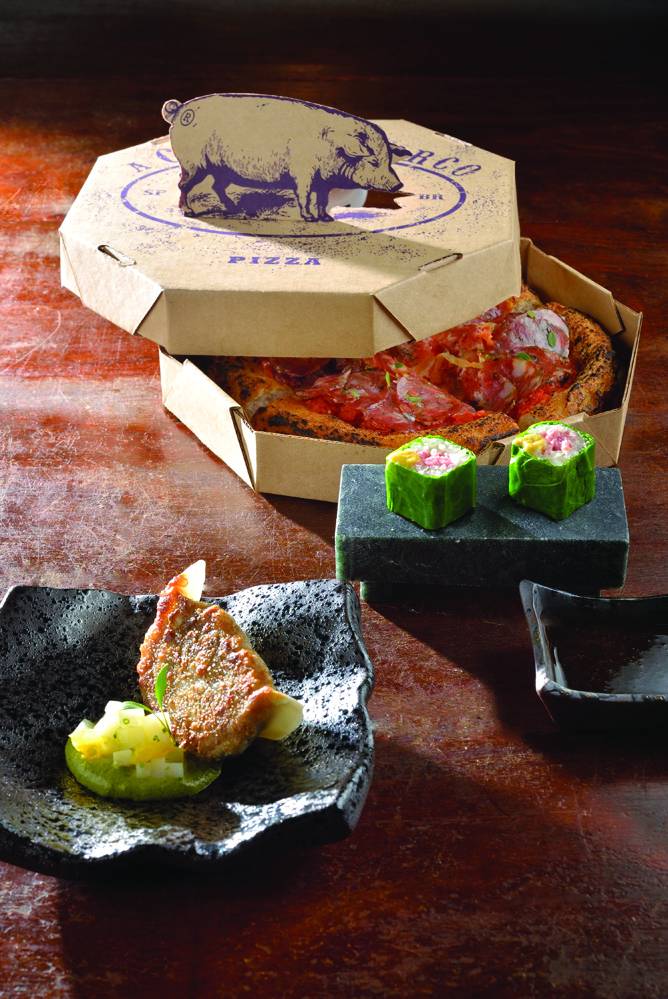 A Casa do Porco_Porco é Pop_Credito Mauro Holanda 1.JPG Caixa com pizza e pratos com comidas em cima de mesa