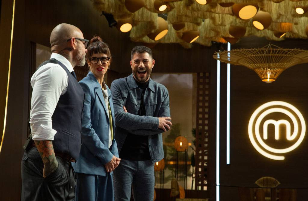 Alessandra Gerzoschkowitz_credito_010 No cenário do MasterChef, estão três pessoas de pé: Henrique Fogaça, Helena Rizzo e Evaristo Costa