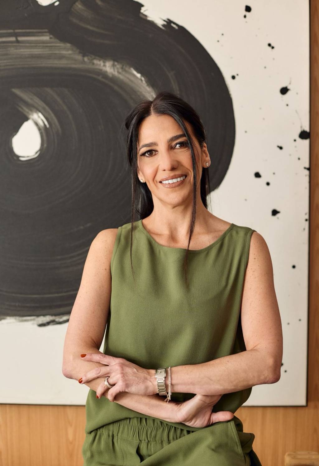 Carol Burg Mulher de cabelos pretos sorri, veste vestido verde escuro.