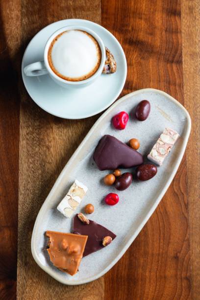 Degustação da Hagi: torrones, crocante aerado de mel com chocolate, drágeas, e “telhas” de chocolate ao lado do macchiato