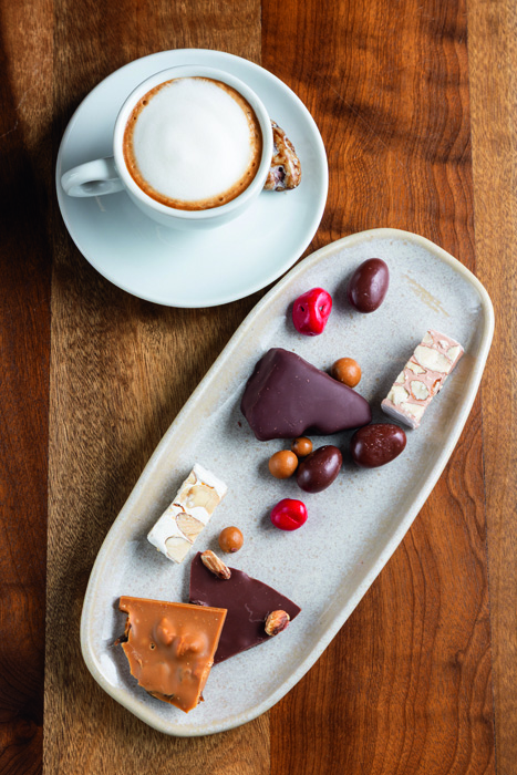 Degustação da Hagi: torrones, crocante aerado de mel com chocolate, drágeas, e “telhas” de chocolate ao lado do macchiato Degustação da Hagi: torrones, crocante aerado de mel com chocolate, drágeas, e “telhas” de chocolate ao lado do macchiato