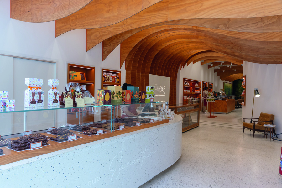 Espaço grande com telhado de madeira e chão branco e vitrine de vidro