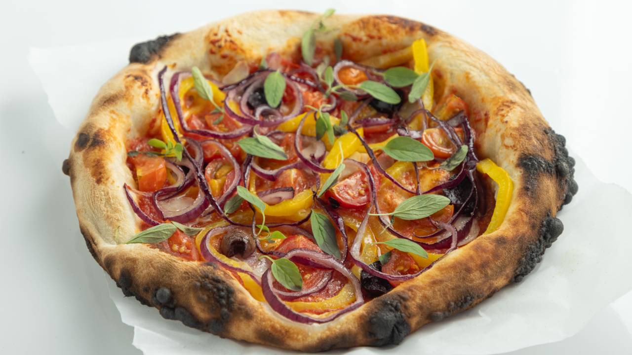 Pizza com tomates, azeitona preta e verdinho em cima