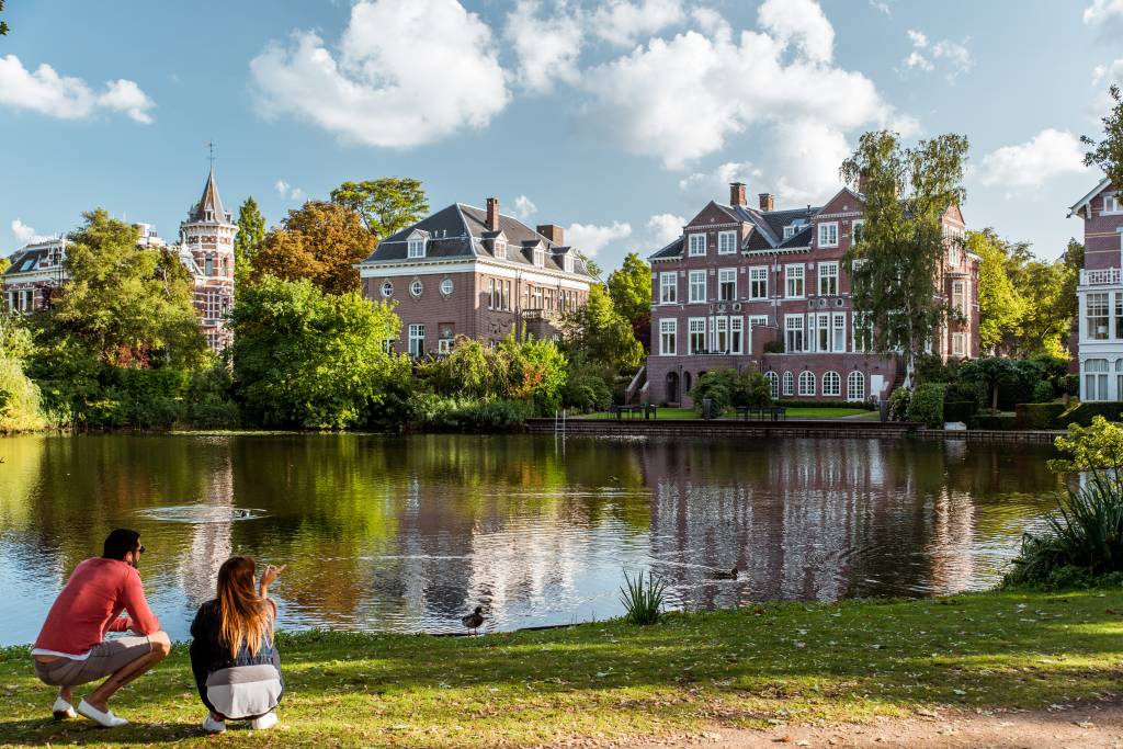 Villa at the Vondelpark-Koen Smilde Photography-Rechtenvrij Crédito Koen Smilde Photography Parque com duas pessoas à esquerda, lago e ao fundo casas