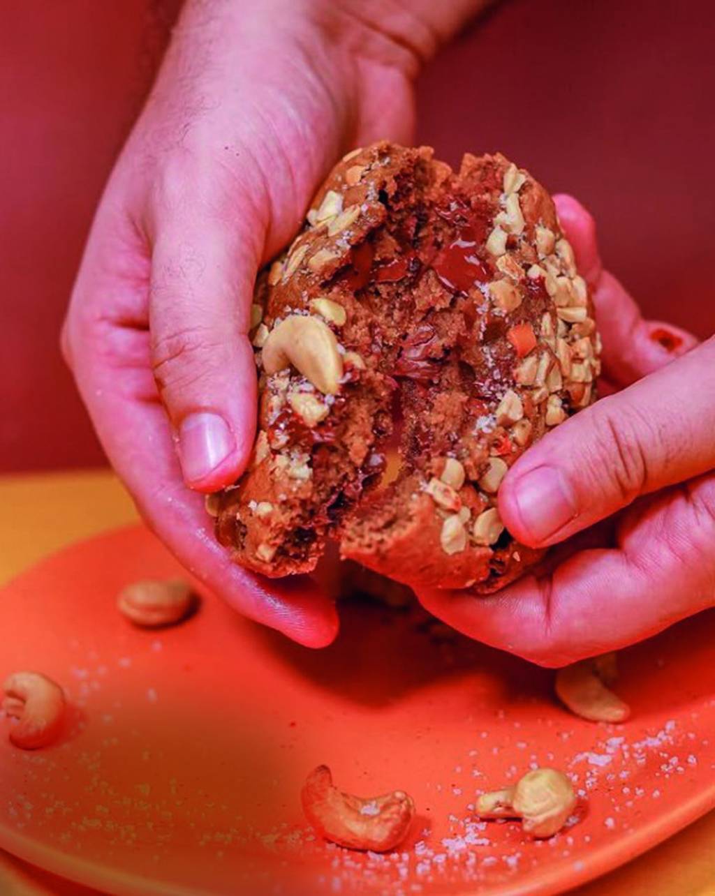cajookie – FALTA CREDITO.jpg Pessoa segurando o cookie e quebrando, com castanhas